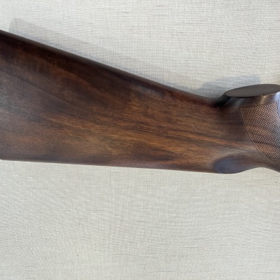 Cabo de madeira de arma de fogo castanha com textura no punho sobre superfície clara