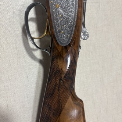Carabina de madeira e metal gravada com padrão floral numa parede texturizada clara
