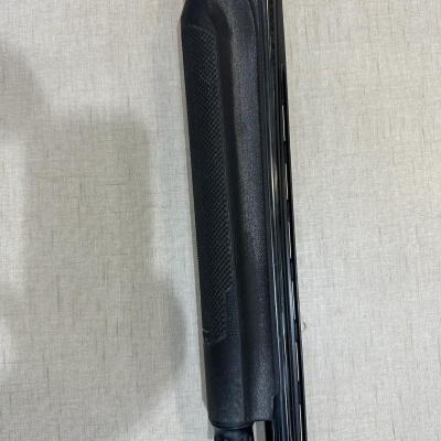 Punho preto texturizado de um objeto longo sobre superfície clara.