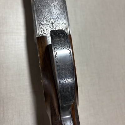 Parte superior e gatilho de arma de fogo em madeira e metal com gravações detalhadas.