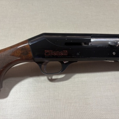 Espingarda Benelli com madeira e metal sobre superfície clara