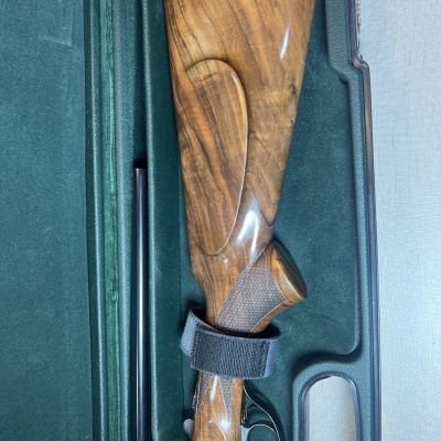 Espingarda desmontada com coronha de madeira polida numa caixa de transporte acolchoada