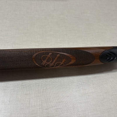 Punho de espingarda em madeira castanha com logotipo e detalhe preto.