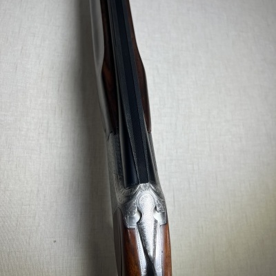 Espingarda com canos pretos e acabamentos em metal e madeira
