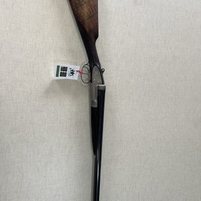 Espingarda de cano duplo com coronha de madeira escura e etiqueta pendurada