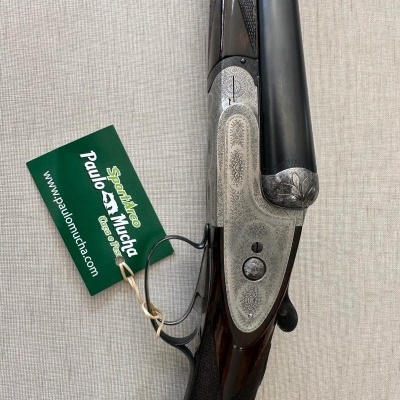 Espingarda de caça sobreposta com madeira e metal prateado gravado e etiqueta verde da marca