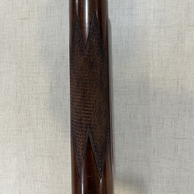 Cano de arma de fogo em madeira com padrão zig-zag e metal nas extremidades