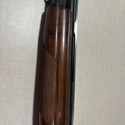 Parte da coronha de madeira e corpo metálico de arma de fogo