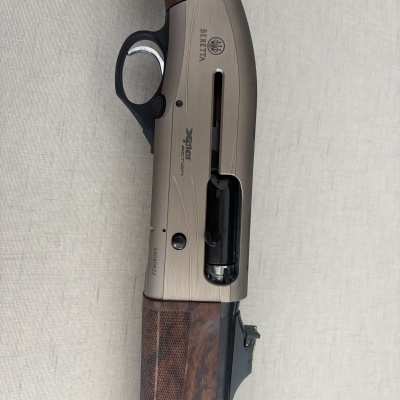 Espingarda Beretta Xplor Action com corpo metálico bege e cabo em madeira escura.