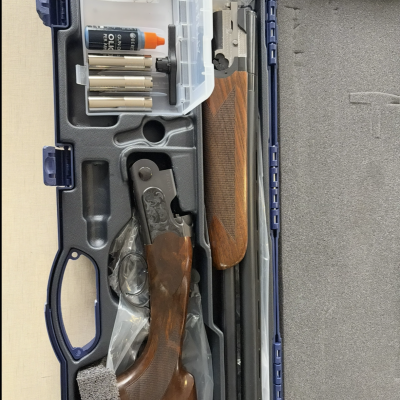 Estojo aberto com espingarda desmontada e acessórios