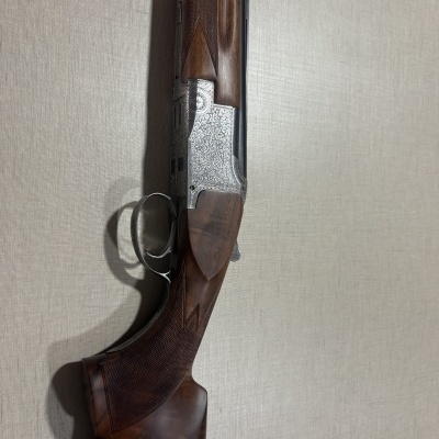 Espingarda de madeira e metal com gravações ornamentais pendurada na parede