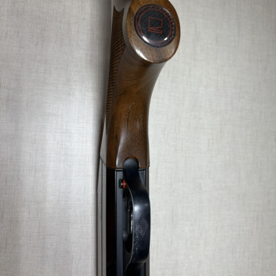 Arma de fogo com cabo em madeira e parte metálica preta em fundo neutro