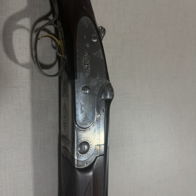 Espingarda de caça de madeira escura e metal gravado com texto J. Purdey