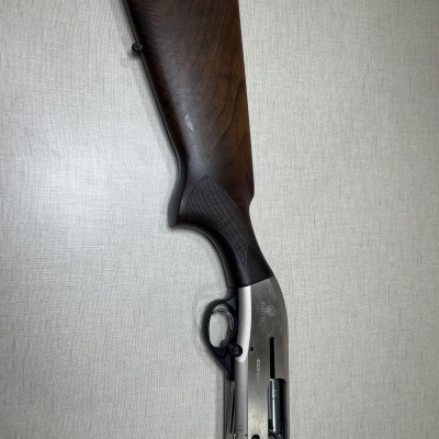 Espingarda com coronha em madeira castanha e acabamento metálico prateado