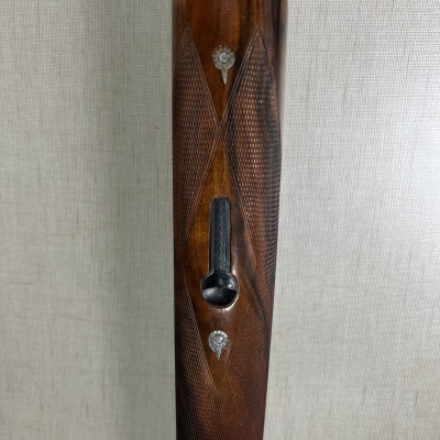 Coronha de arma em madeira escura com entalhes e rosetas metálicas