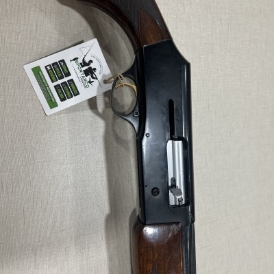 Espingarda semiautomática com madeira castanha e corpo metálico preto em tecido bege