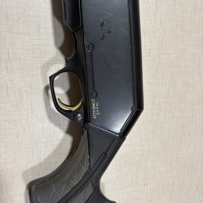 Carabina preta com gatilho dourado e empunhadura texturada cinza