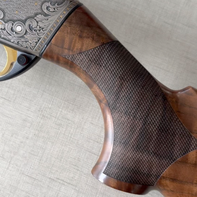 Coronha de espingarda em madeira com textura quadriculada e ornamentos metálicos gravados