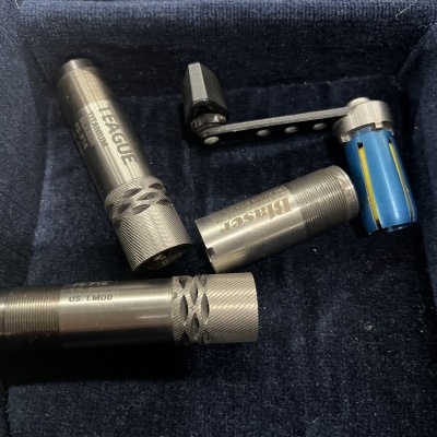 Três tubos metálicos prateados e suporte azul com alavanca preta em superfície azul escura aveludada.