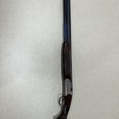 Espingarda de canos duplos em madeira e metal contra parede branca