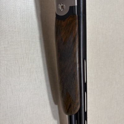 Espingarda com empunhadura de madeira e cano preto encostada na parede