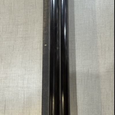 Objeto cilíndrico preto sobre fundo tecido cinza claro