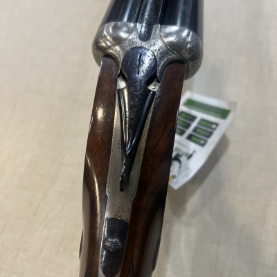 Espingarda de canos duplos e madeira escura com detalhes metálicos