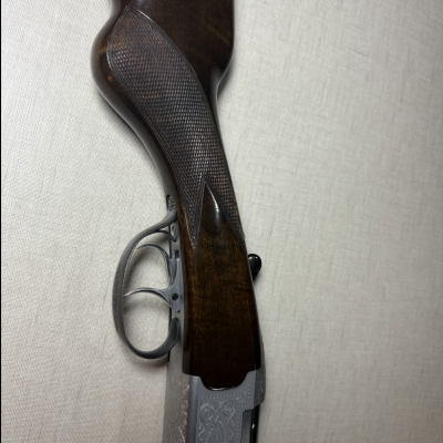 Coronha de arma de fogo em madeira escura com detalhes metálicos gravados e dois gatilhos