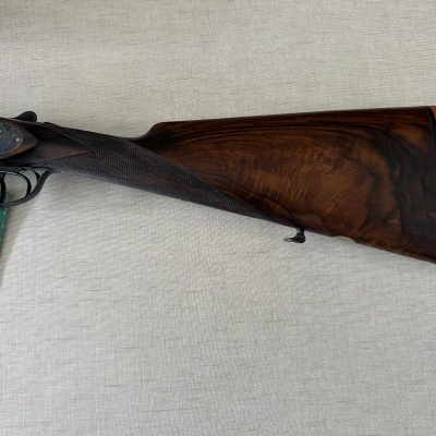 Espingarda de madeira castanha escura e metal preto com etiqueta verde