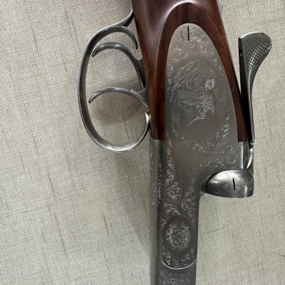 Espingarda de canos duplos com gravuras florais e de cães e madeira castanha polida sobre tecido cinza