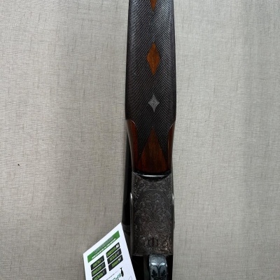 Espingarda com empunhadura em madeira entalhada e corpo metálico decorado