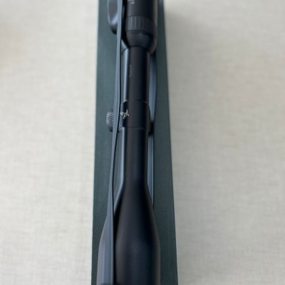 Mira telescópica preta montada em arma sobre fundo claro