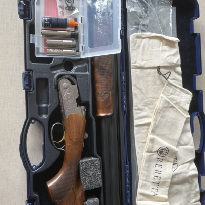 Estojo aberto contendo espingarda Beretta, acessórios e pano branco com logo Beretta