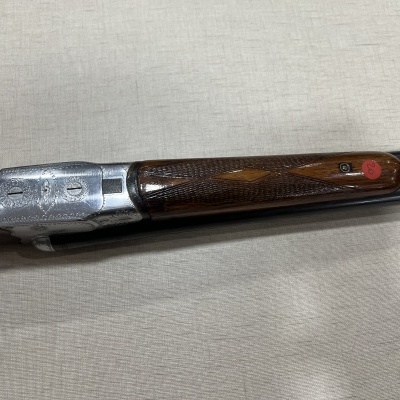 Espingarda de cano duplo com madeira escura e detalhes metálicos prateados