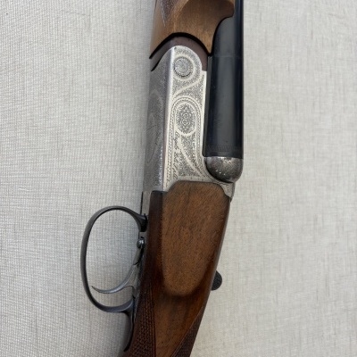 Espingarda de caça com coronha de madeira e detalhes entalhados.