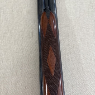 Parte frontal de arma com madeira trabalhada e cano duplo preto