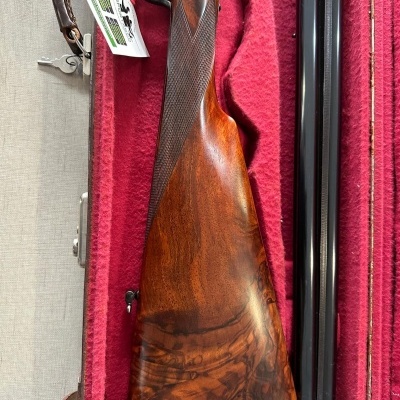 Espingarda de caça com coronha em madeira castanha e canos pretos em estojo vermelho acolchoado
