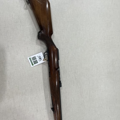 Espingarda com coronha de madeira castanha e cano preto sobre superfície clara.