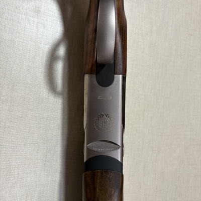 Arma de fogo com detalhes em metal prateado e madeira castanha com inscrições visíveis