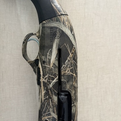 Parte da espingarda Beretta camuflada com detalhes em preto e padrão natural