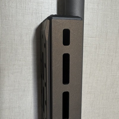 Dispositivo metálico cinza escuro com ventilação, ligado a tubo preto, junto a parede cinza texturada