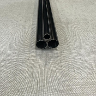 Três tubos cilíndricos pretos de metal sobre superfície cinzenta