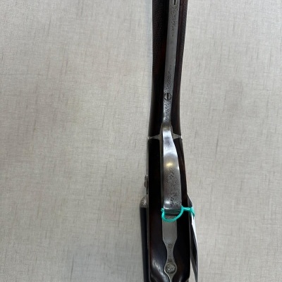 Rifle de cano duplo com madeira castanha e detalhes em metal prateado