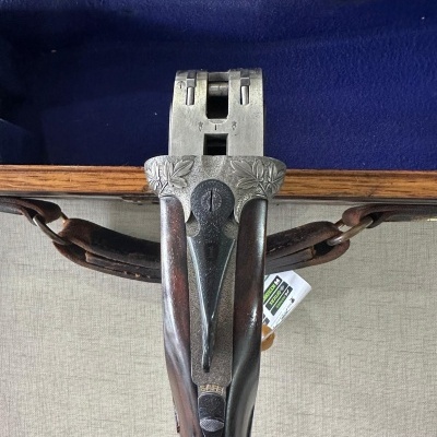 Espingarda com coronha de madeira e armação metálica prateada com detalhes florais na mala azul