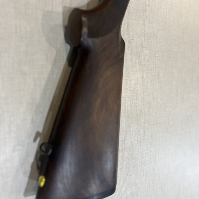 Coronha de espingarda em madeira escura montada numa parede clara