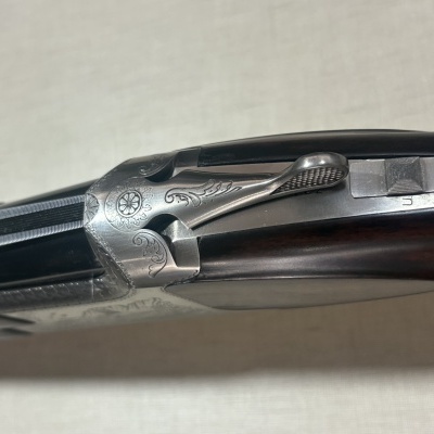 Espingarda de canos duplos em metal prateado com gravações e madeira escura