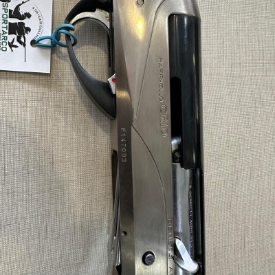 Espingarda metálica prateada com empunhadura de madeira e inscrições gravadas