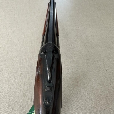 Espingarda de canos duplos com coronha de madeira escura sobre tecido bege