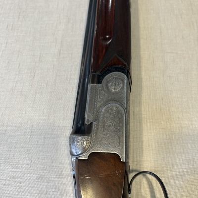 Espingarda de canos duplos com madeira e metal gravado sobre superfície clara