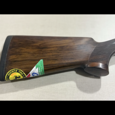 Parte traseira de arma de fogo em madeira escura com adesivos coloridos